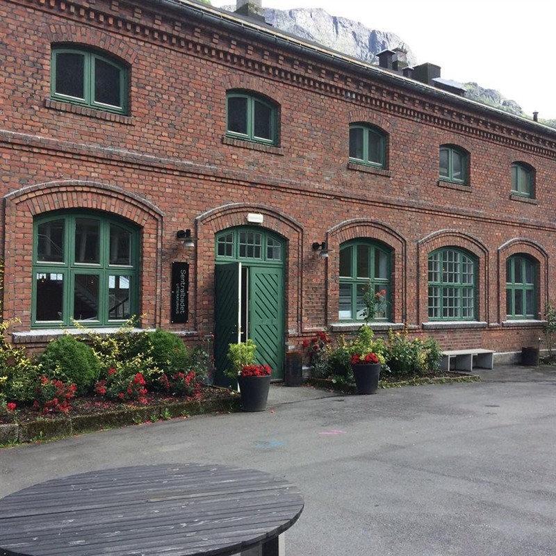 Raud teglsteinsbygning med grøne vindauge. Bilete.