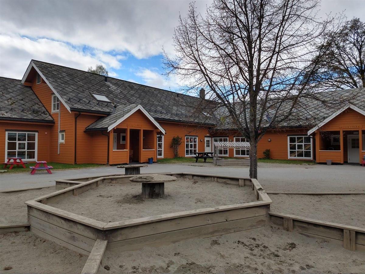 Orange bygning med sandkasse i framgrunn. Bilete. - Klikk for stort bilete