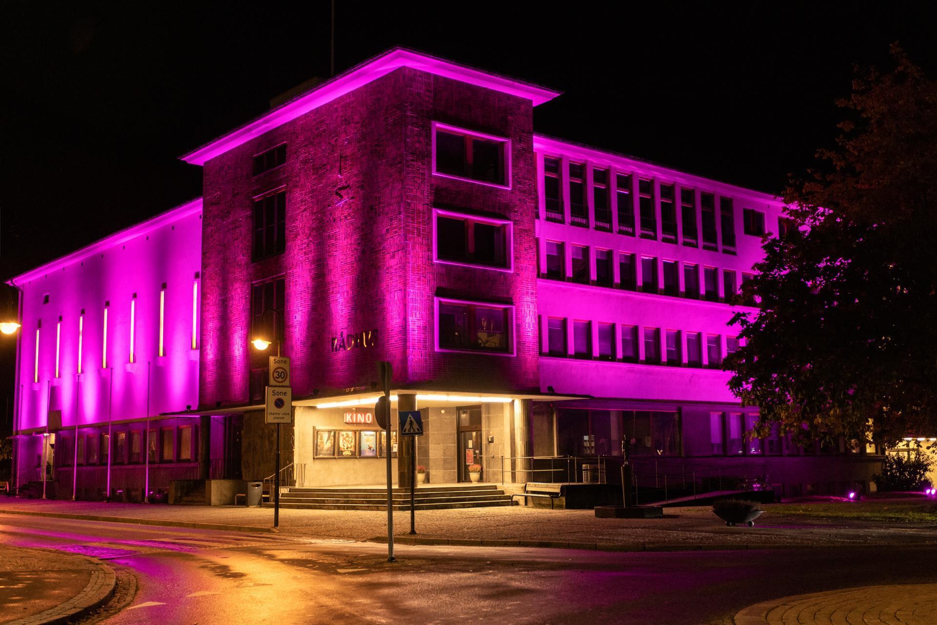 Rådhuset i Odda ein sein kveld lyssett i lilla lys. Foto.