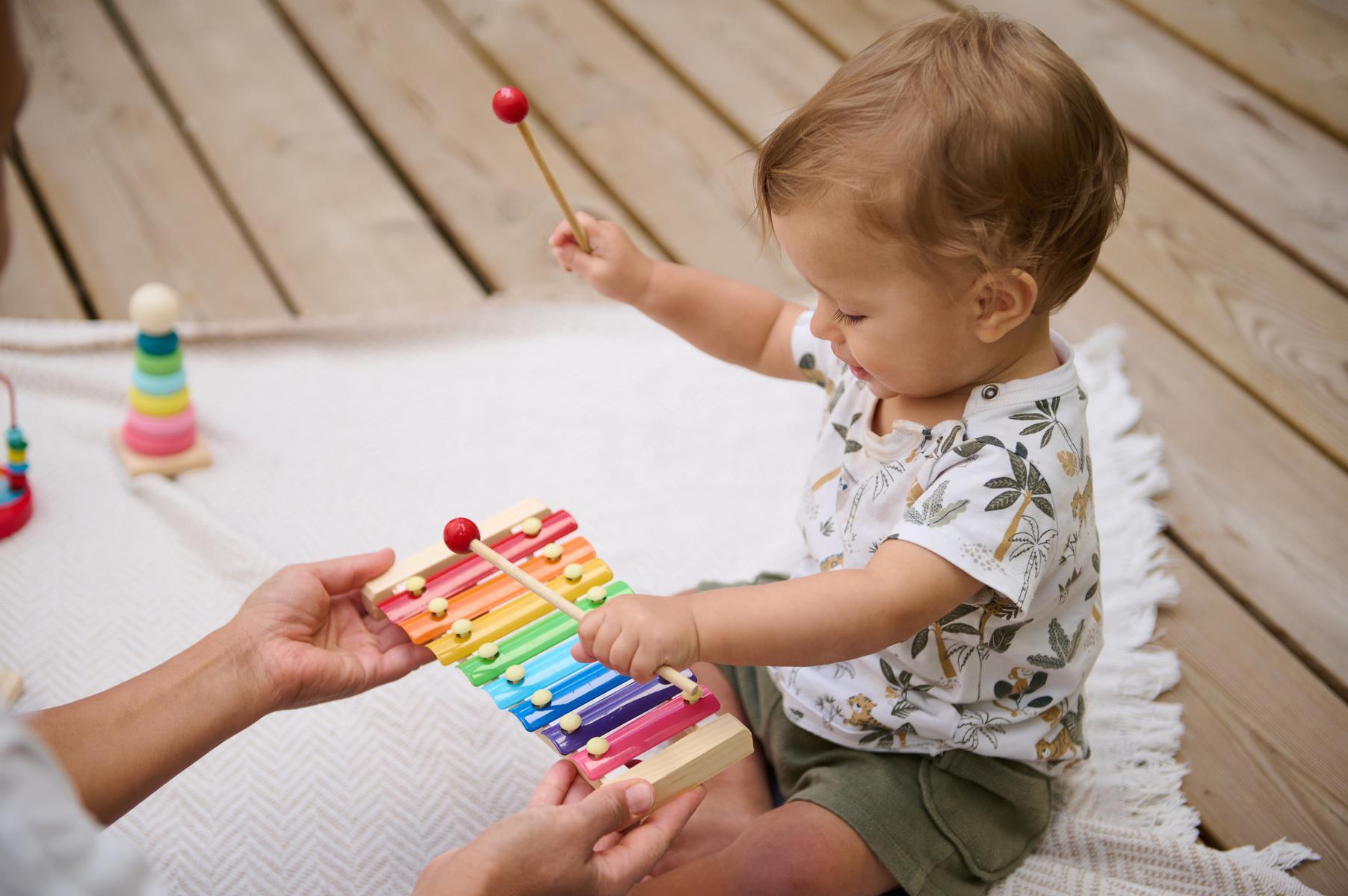 Liten gutt som sitter og spiller på instrument. Bilete.