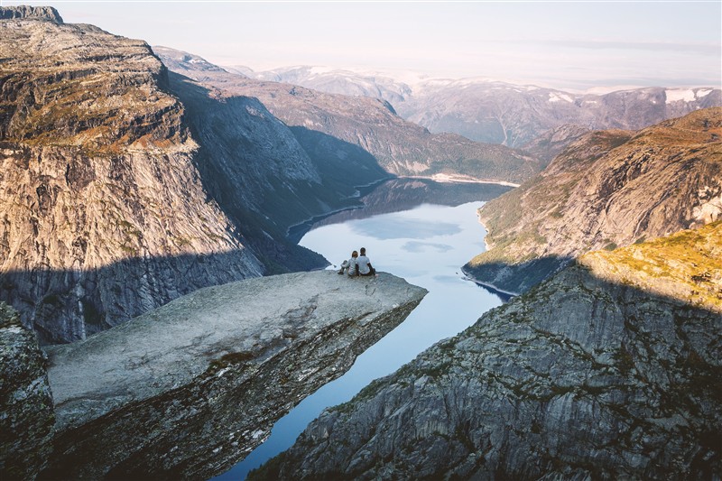 To personer som sitter på Trolltunga og ser utover Ringedalsvatnet. Bilete.