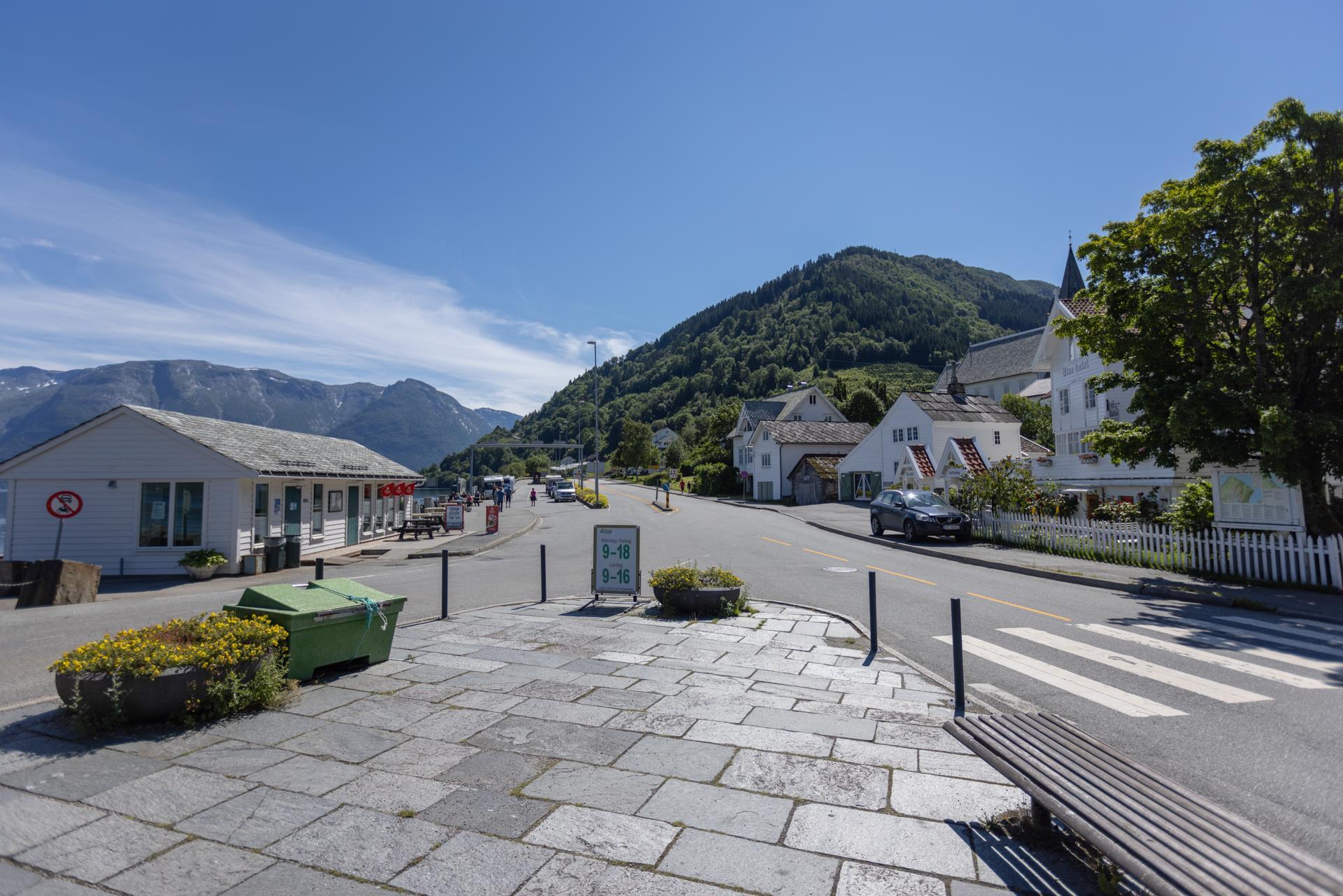 Fint skiferbelagt fortau med utsyn over Utne sentrum ein fin sommardag. Bilete.