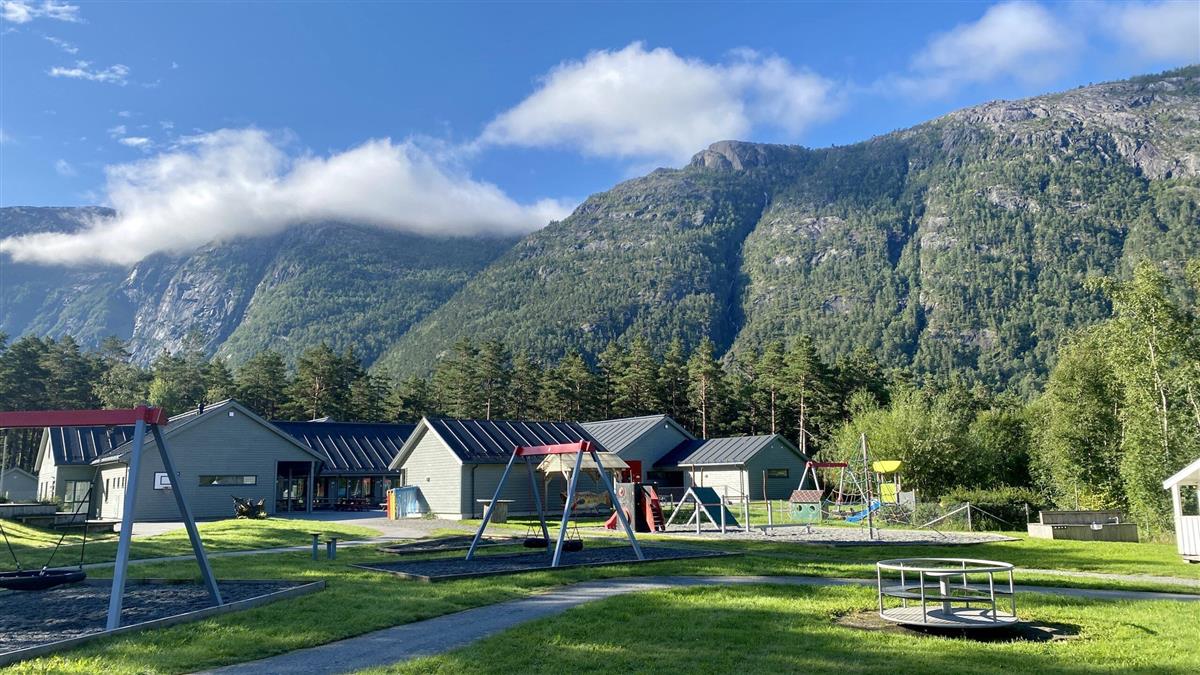 Kinsarvik barnehage med fjell og blå himmel i bakgrunn. Bilete. - Klikk for stort bilete