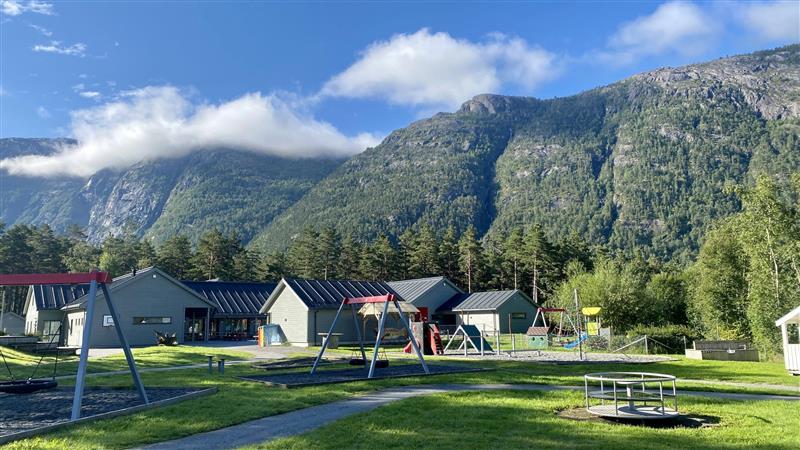 Kinsarvik barnehage med fjell og blå himmel i bakgrunn. Bilete.