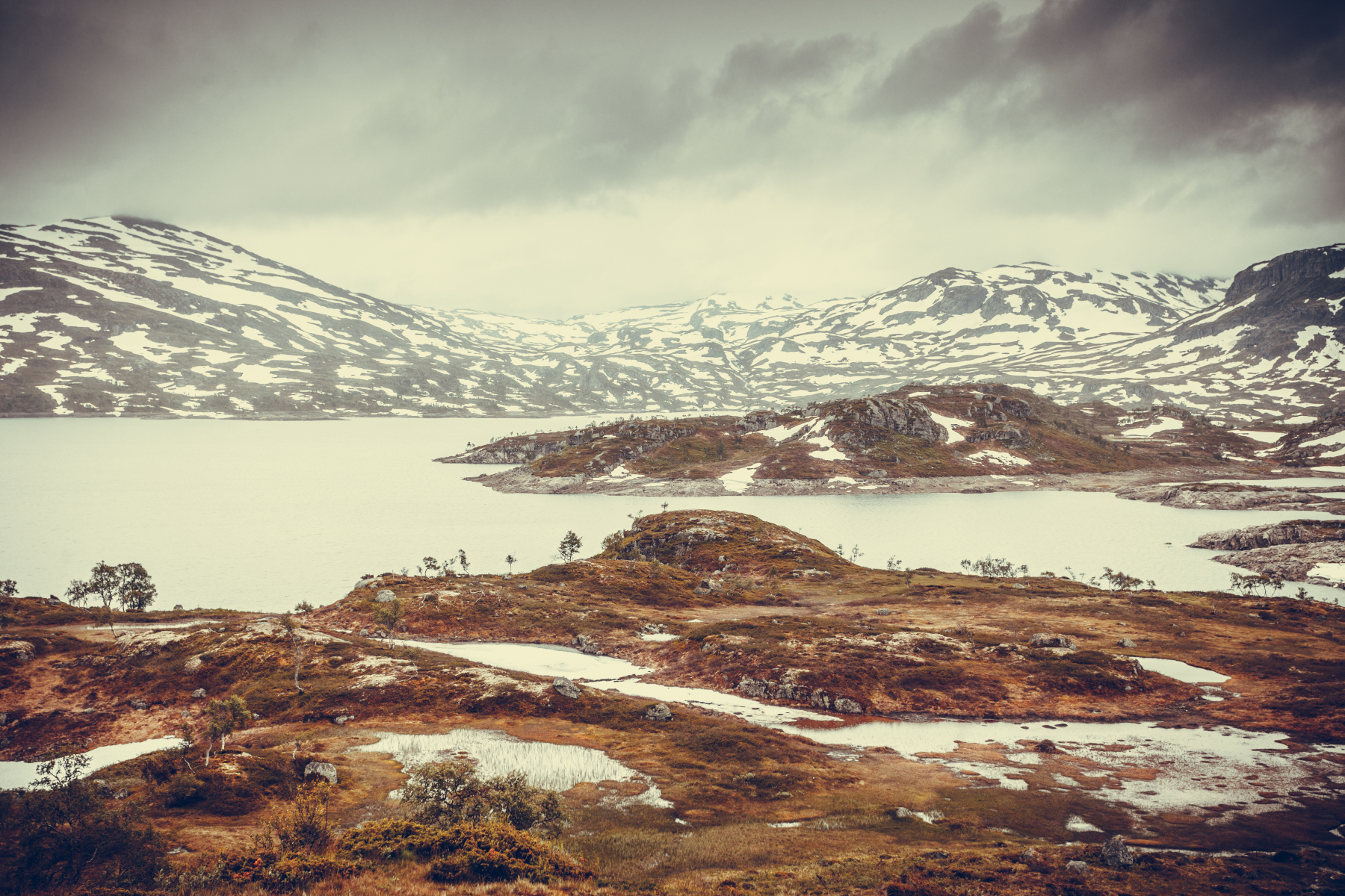 Utsyn over Hardangervidda nasjonalpark om hausten med snø, vatn og fjell. Foto.