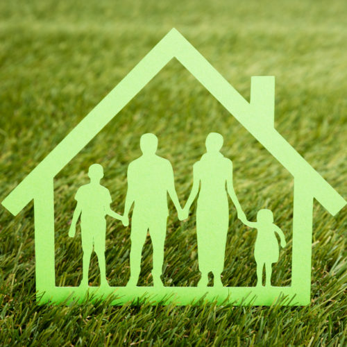 Grønt ikon av familie inne i eit hus med gras som bakgrunn. Foto.