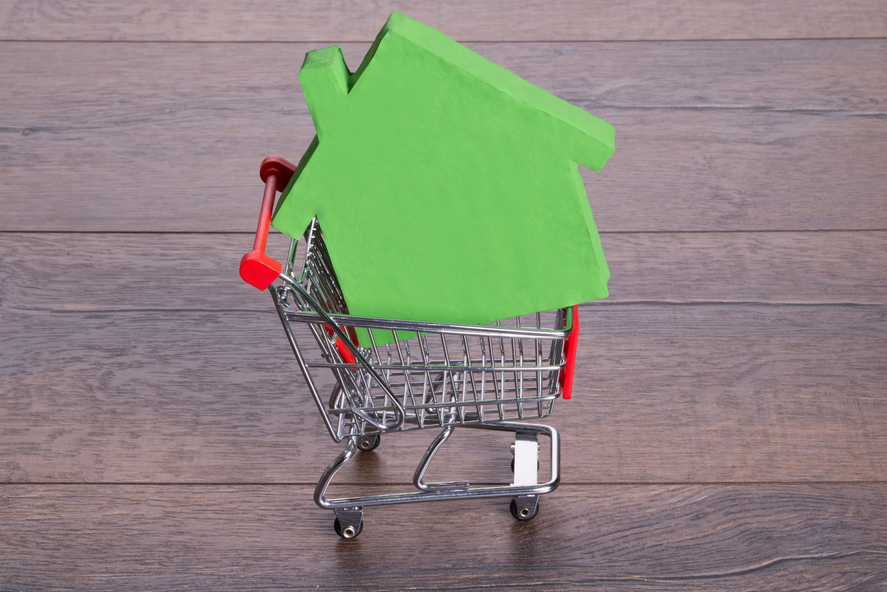 Grønt modellhus oppe i handlekurv