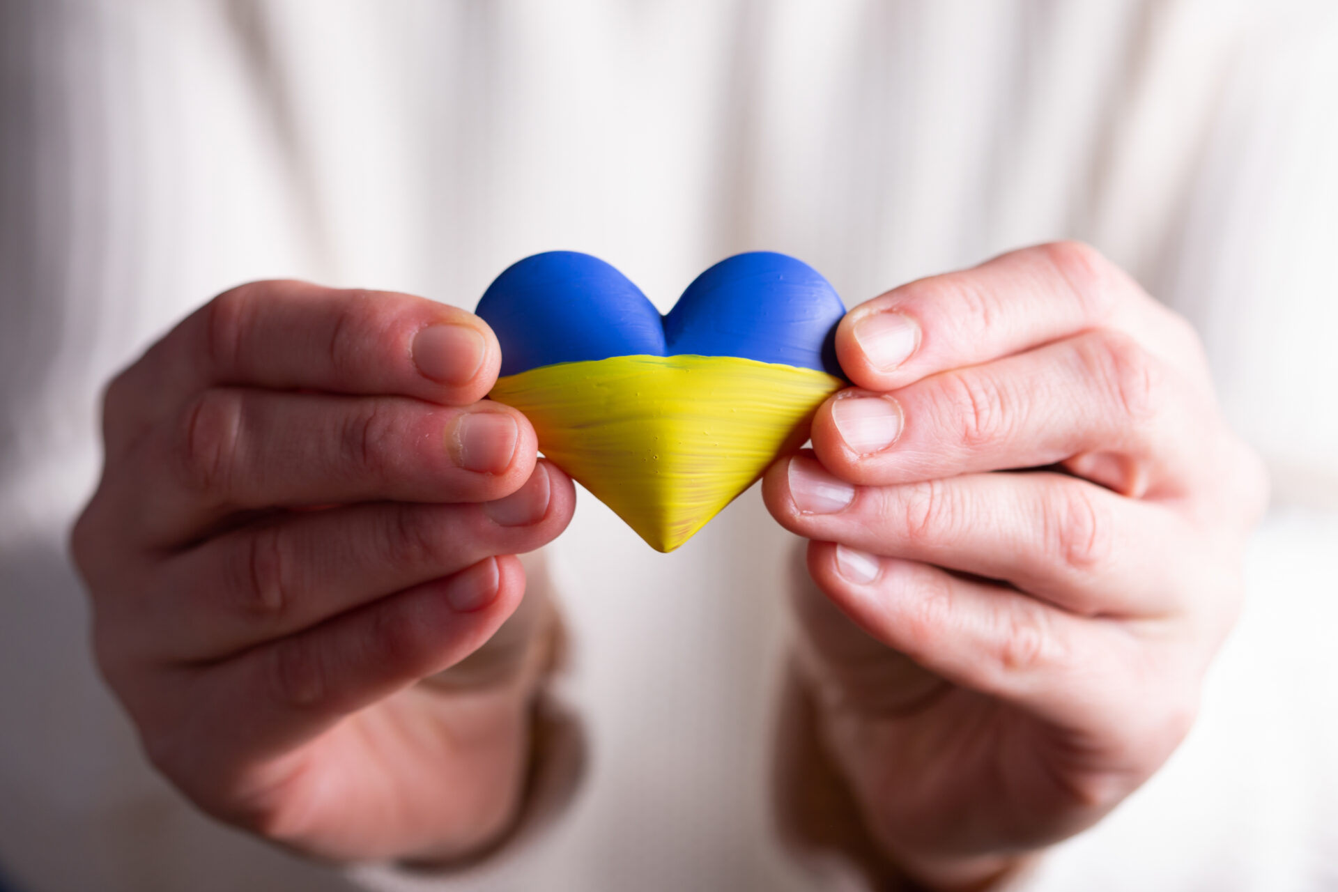 Heart shaped flag of Ukraine in female hands. The concept of solidarity with the citizens of Ukraine.